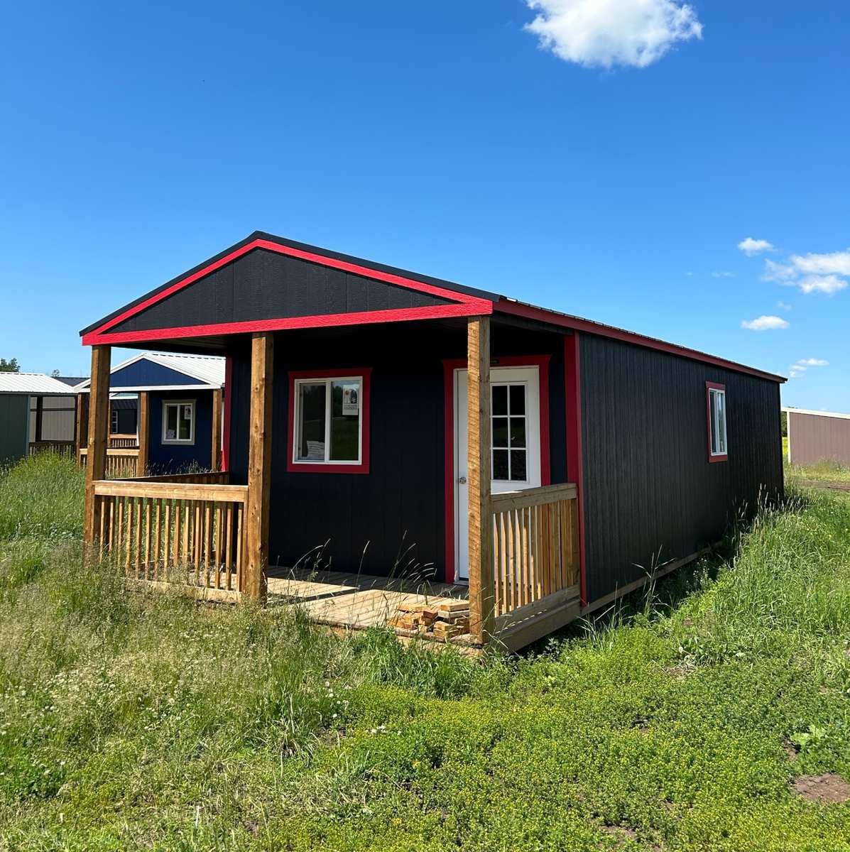 Premier black gabled portable cabin with red trim and covered front porch, delivered across Alberta