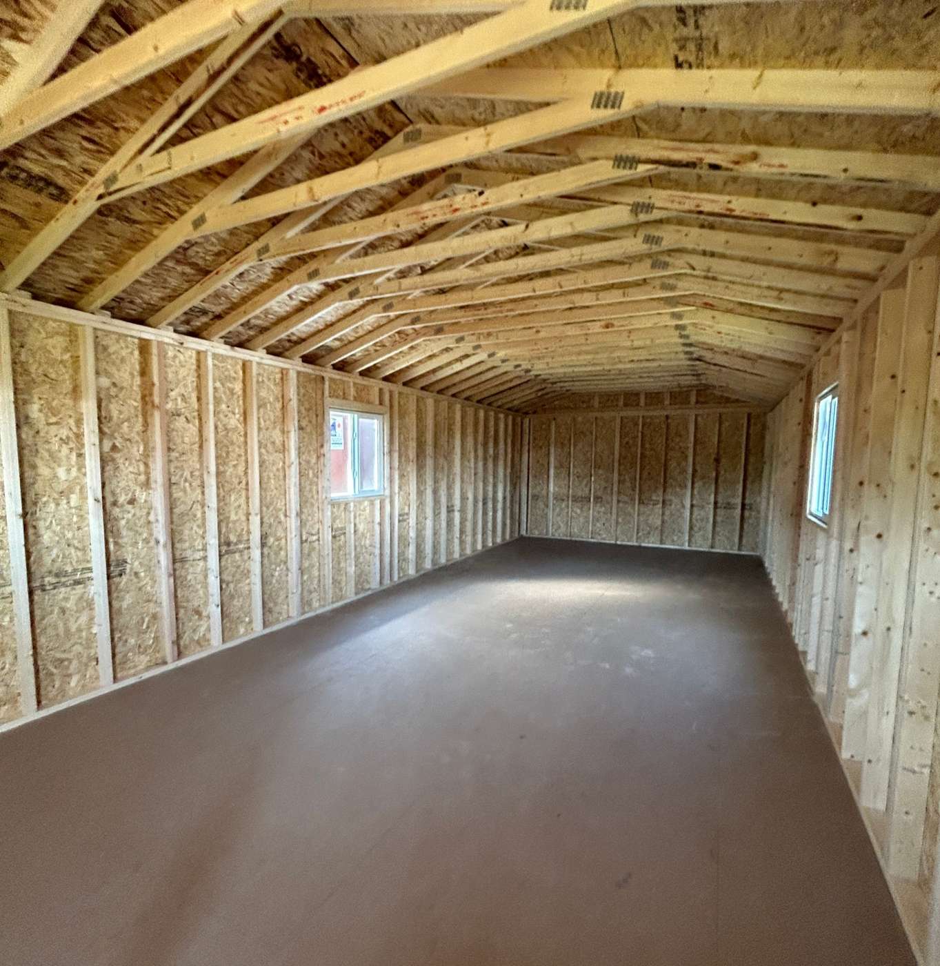 Interior view of Premier gabled cabin with open trusses, OSB walls and painted floor in Alberta